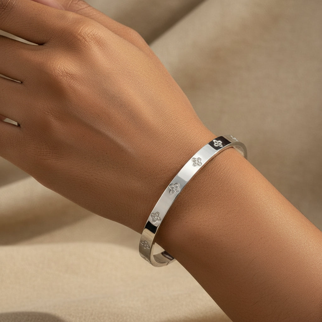 Silver bracelet with floral designs on a beige fabric background