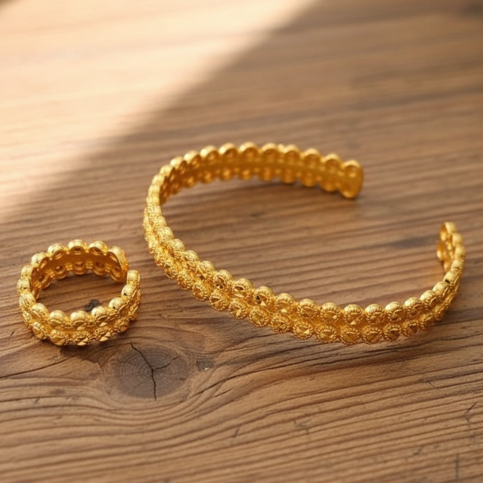 Gold bracelet and ring on a beige fabric background