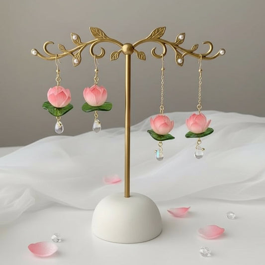 Gold earring stand with pink floral earrings on a white surface