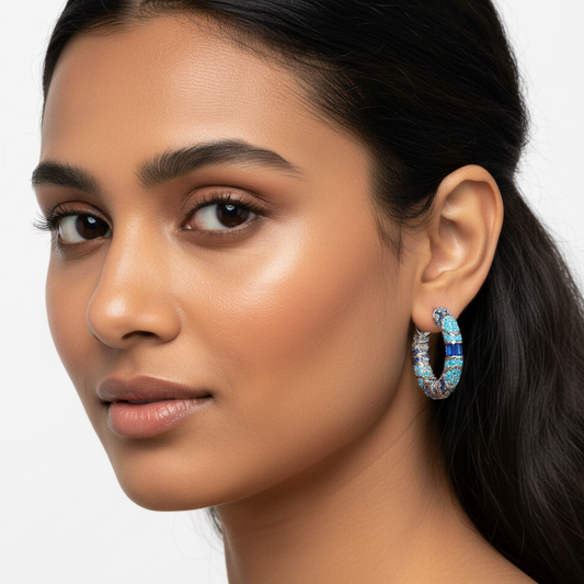 Close-up of a woman wearing a hoop earring with blue and silver accents on a white background
