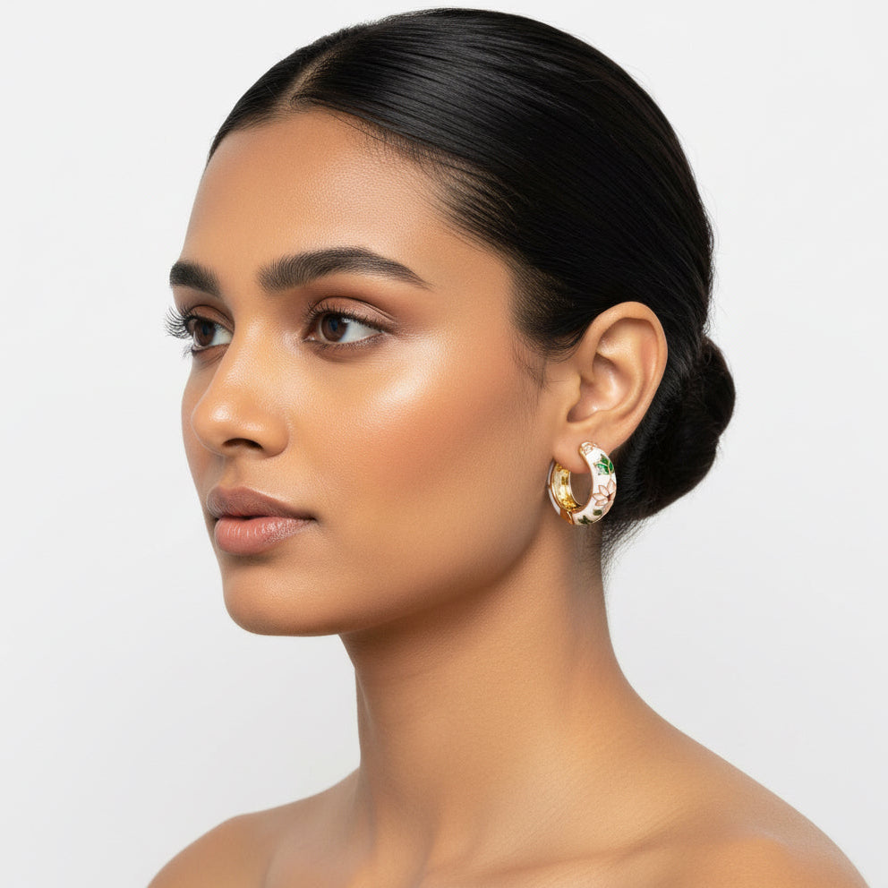 Woman wearing gold hoop earrings on a plain background