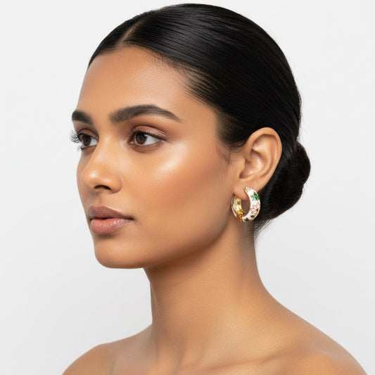 Woman wearing gold hoop earrings on a plain background