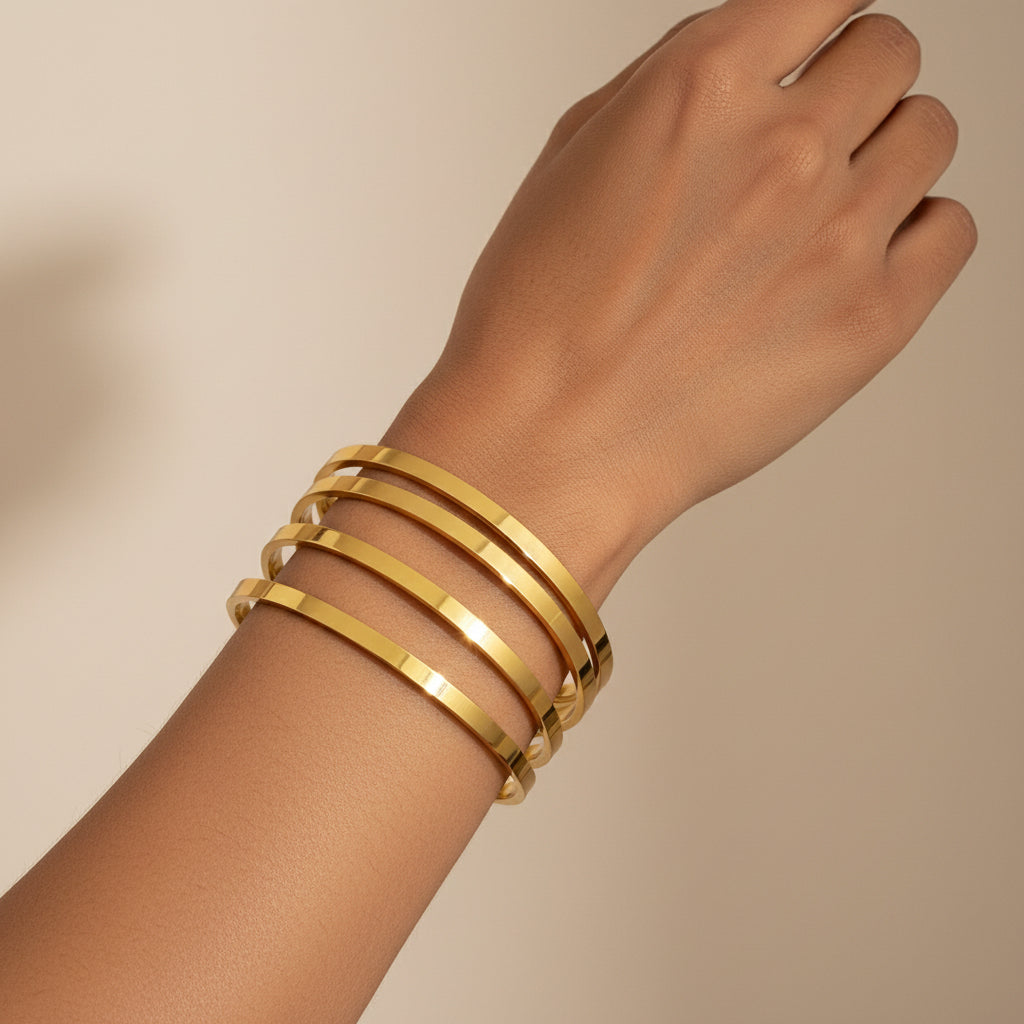 Three gold bangles stacked on a textured white surface