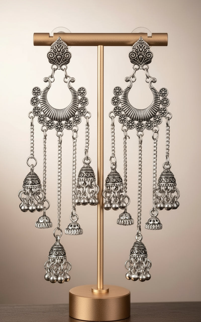 Pair of silver earrings with intricate designs on a black background