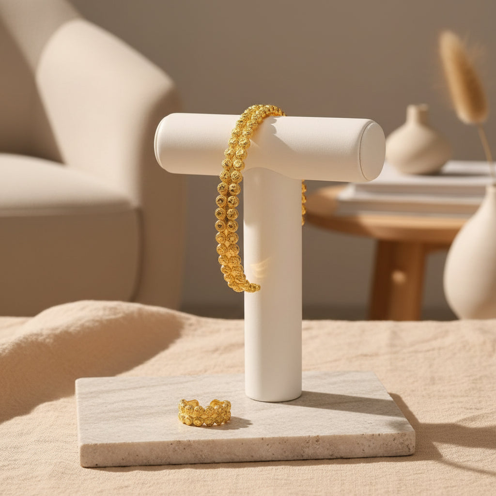 Gold bracelet and earrings on a beige surface