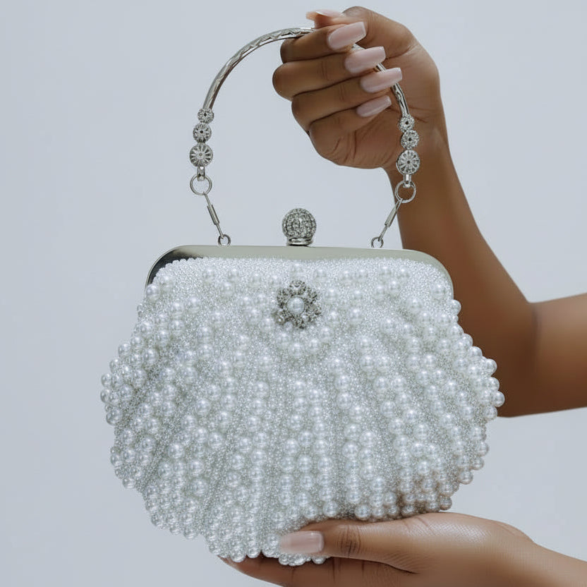 White beaded handbag held by a hand against a light gray background